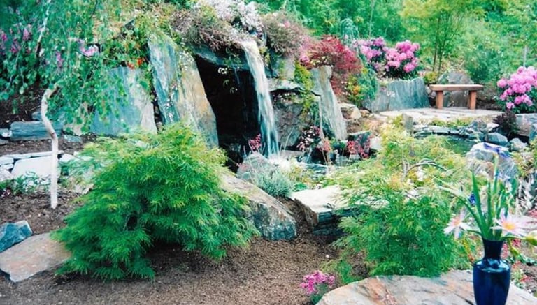 Slate stone grotto with hidden hot tub behind waterfall flowing into natural pool. Carmel Valley, CA