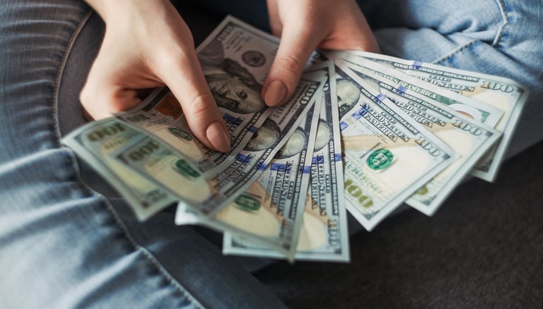 person holding a wad of 100 dollar bills in their hand