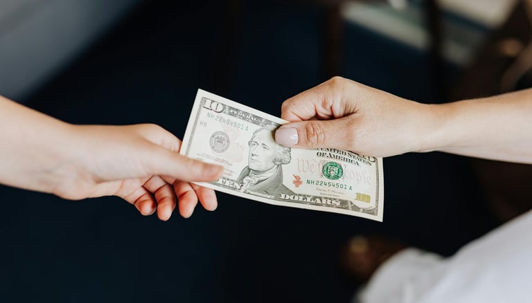 two people holding onto a dollar bill representing blog post about gold ira fees and a guide to understanding gold ira fees