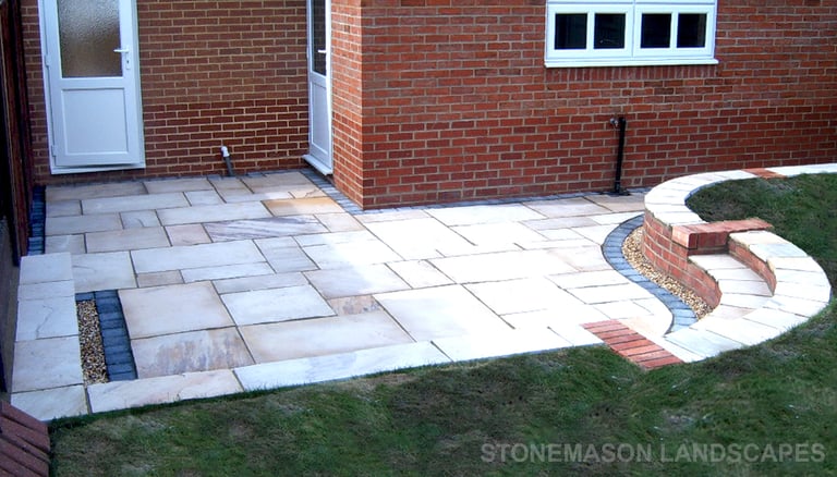Multi-level sunken sandstone patio step up to lawn with retaining wall