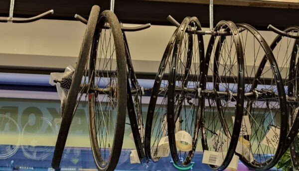 a bunch of bike wheels hanging from a rack in turku pyörähuolto