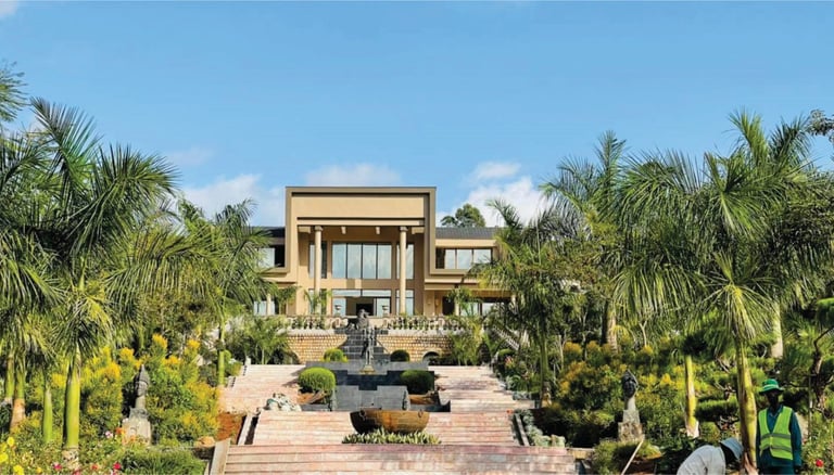 Un grand bâtiment qui est le centre climatique de Dschang avec une fontaine au milieu d'un jardin