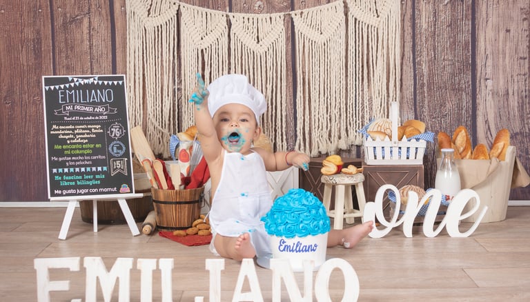 a baby boy in a white dress and a cake