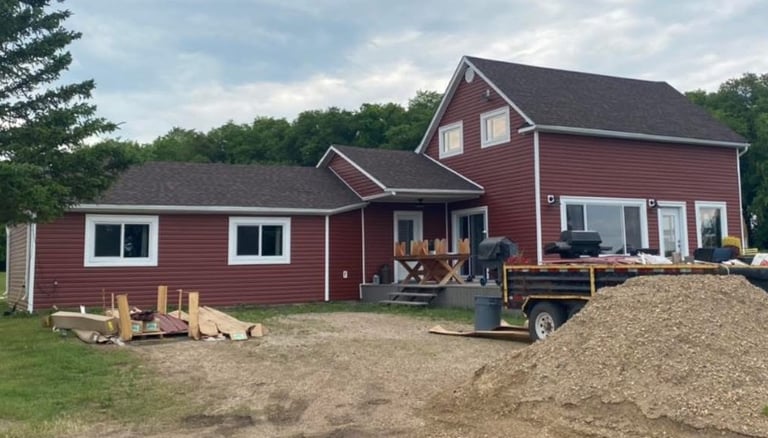 Red vinyl siding on a modern two-story country house with white window trim and a new shingle roof.