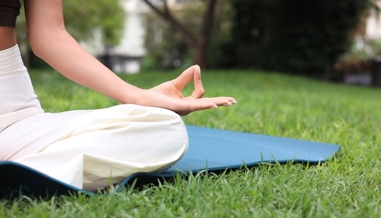 Woman practicing yoga and meditation on a blue mat in a green park for wellness and wellness.