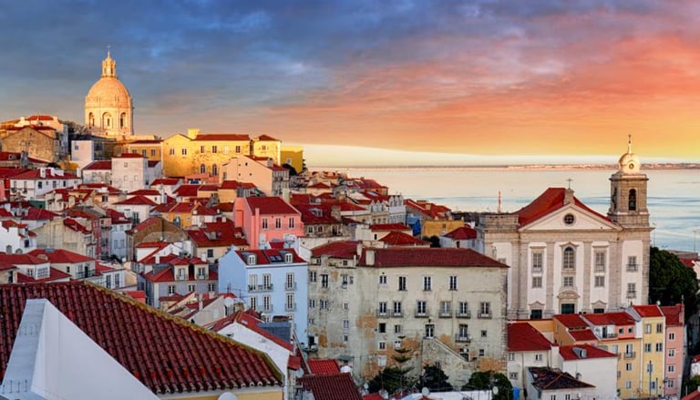Panoramic sunset over Lisbon's Alfama district featuring red tile roofs and the National Pantheon.