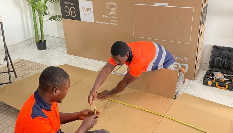 Two professional movers in orange high-visibility vests with reflective stripes carefully measure an