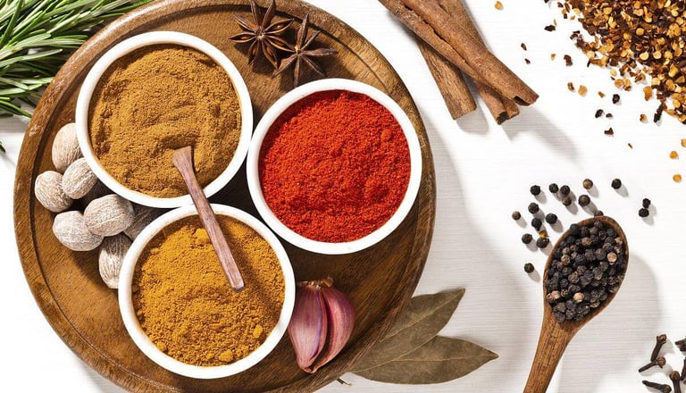Variety of colorful organic spices including turmeric, paprika, and curry powder in bowls with cinnamon sticks.