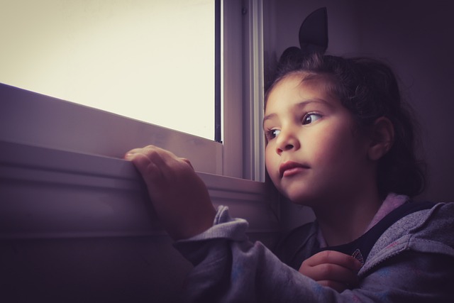 niña sola en casa mirando por una ventana