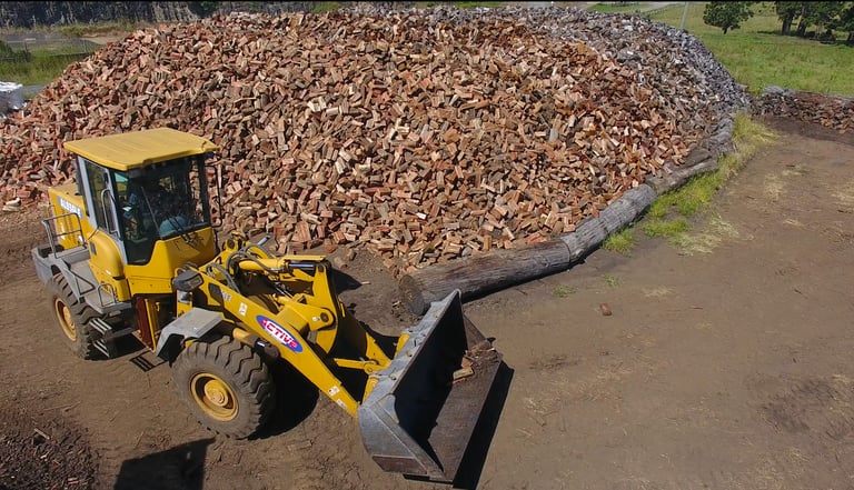 Loader in front of seasoned firewood