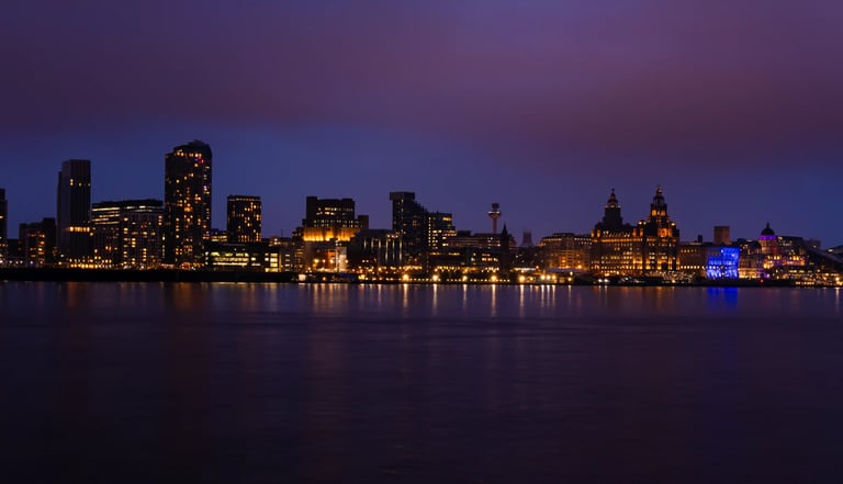 Panoramic Liverpool skyline at night with illuminated buildings reflecting in the River Mersey.