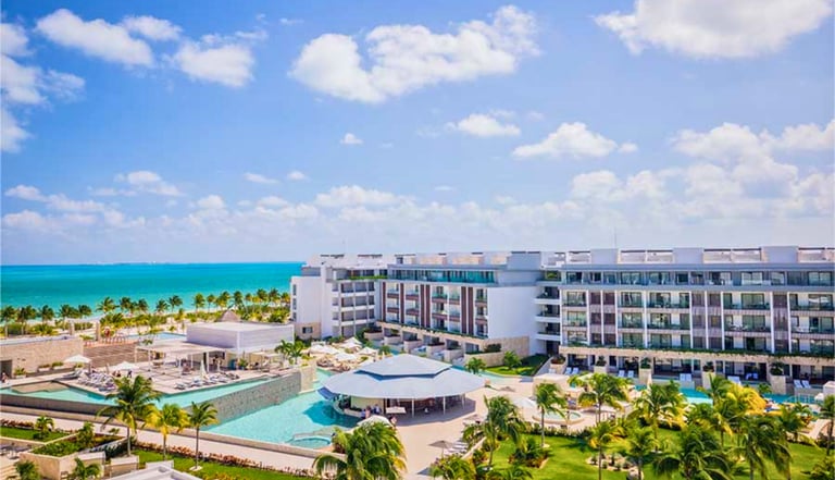 Luxury beachfront resort with turquoise ocean views, tropical palm trees, and swimming pools.