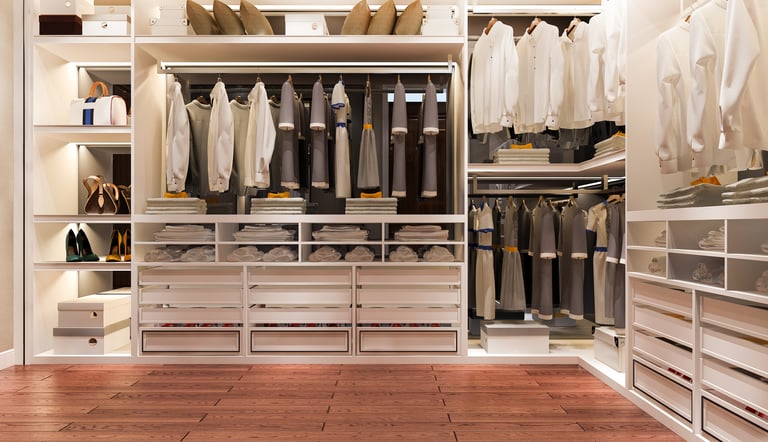 Organized walk-in closet with hanging clothes and storage by KLEAN WELL