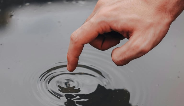 a person's hand is touching a water droplet
