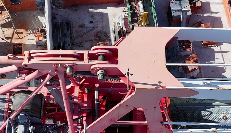 Vue aérienne d'une grue à tour rouge sur un chantier de construction fréquenté avec des matériaux