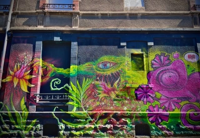 un graffiti d'un monstre vert qui mange des plantes et un caméléon violet