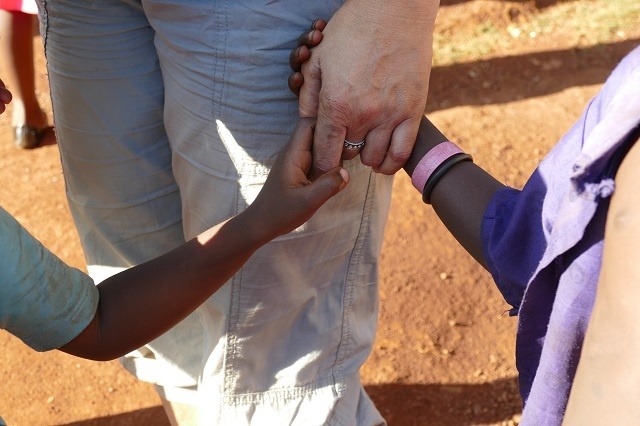 PH-Mitglied hält 2 Kinderhände in einer Hand