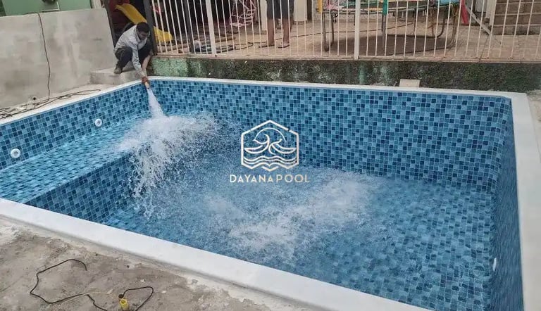 Proses pemasangan material finishing mozaik pada dinding kolam renang oleh tukang berpengalaman.