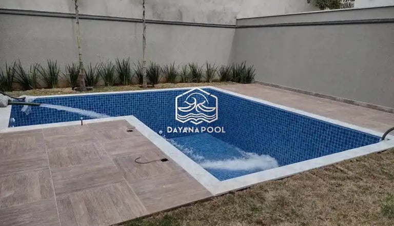 Proses pemasangan material finishing mozaik pada dinding kolam renang oleh tukang berpengalaman.