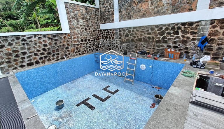 Proses pemasangan material finishing mozaik pada dinding kolam renang oleh tukang berpengalaman.