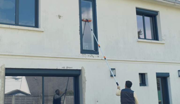 a man is cleaning a house with a window cleaner