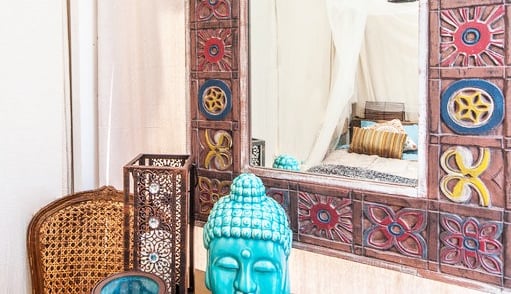 a buddha statue sitting on a table with a mirror