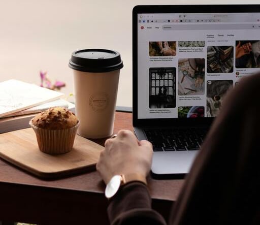 Una persona está navegando por Toty Shopping en un portátil en una cafetería, con una taza de café