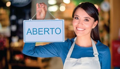 imagem de uma jovem segurando uma placa escrita a palavra ABERTO .