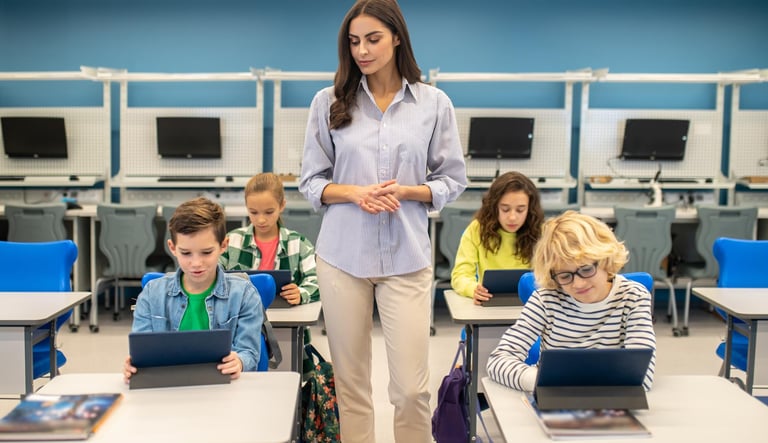 Guru memantau murid yang belajar menggunakan tablet di kelas digital.