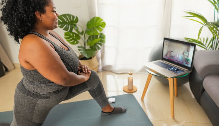 a woman in a gray tank top and gray pants having remote physiotherapy at home with a virtual physio