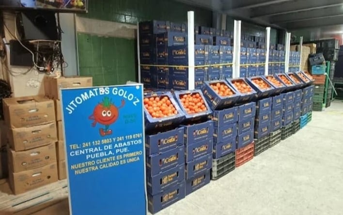 "Bodega de Jitomates Goloz en la Central de Abastos de Puebla, mostrando inventario organizado en ca