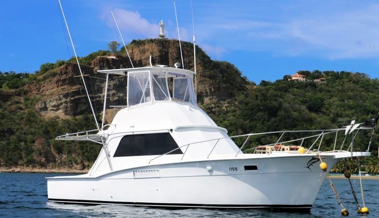 A white Big Fish Tours sportfishing boat anchored in the blue waters of San Juan del Sur, Nicaragua,