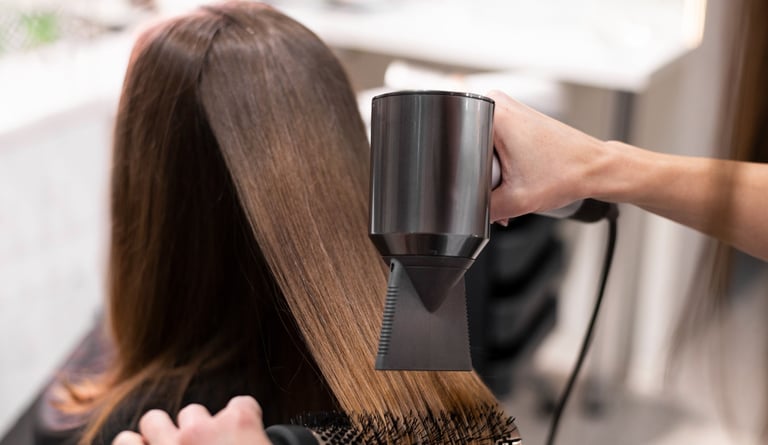 a woman is blow drying her hair in a salon