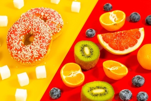 a doughnut and sugar cubes next to fruit