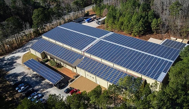 Aerial view of a large commercial solar panel installation on an industrial building roof.