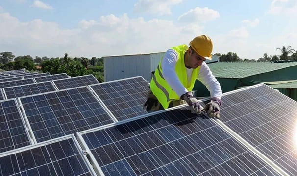 Professional technician installing solar panels on a rooftop for renewable energy efficiency.