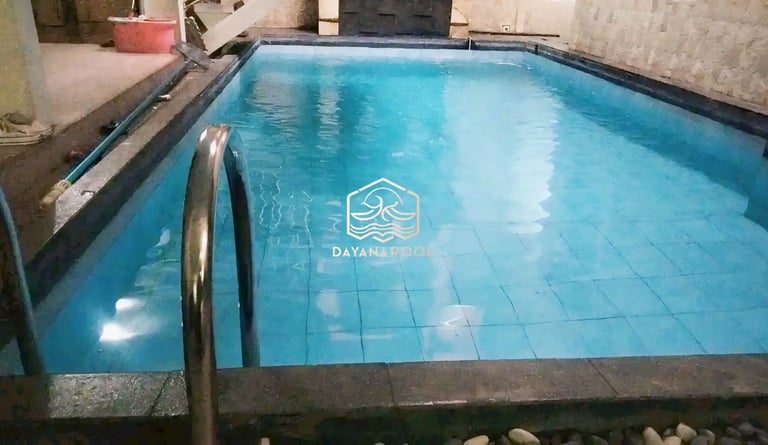 Proses pemasangan material finishing mozaik pada dinding kolam renang oleh tukang berpengalaman.