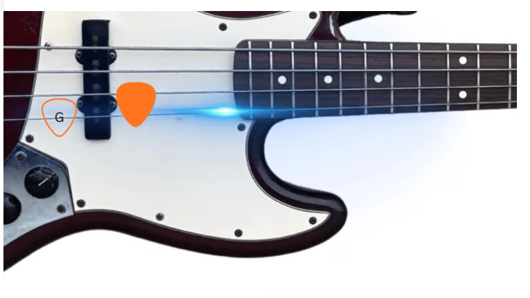 Close-up of an electric bass guitar with orange guitar picks on the strings and pickguard.