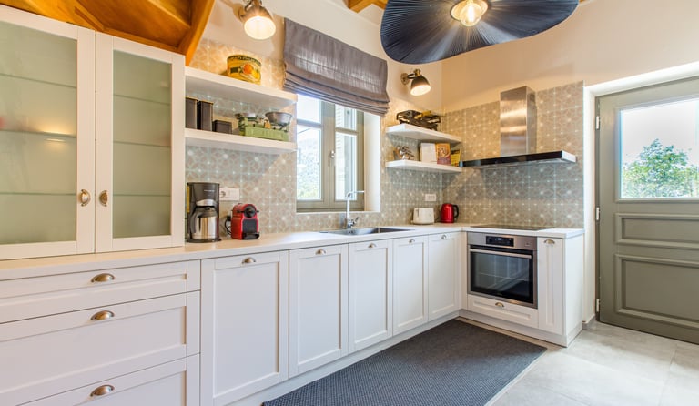Fully equipped kitchen with white cabinets and natural light at Villa Skyphos