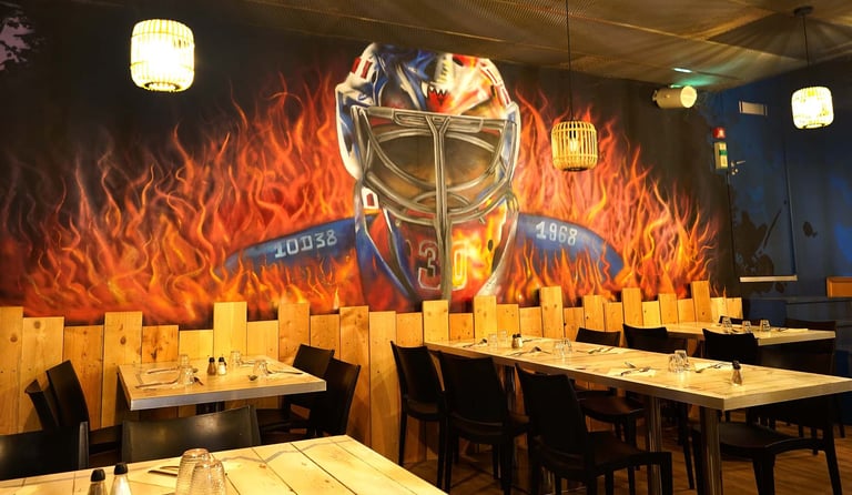 Modern restaurant dining room featuring a mural of a hockey goalie mask and flames.