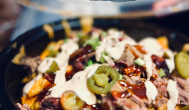 BBQ brisket nachos topped with cheddar cheese sauce, jalapeños, green onions, and house BBQ drizzle—Not Yo Mama’s Nachos, bol