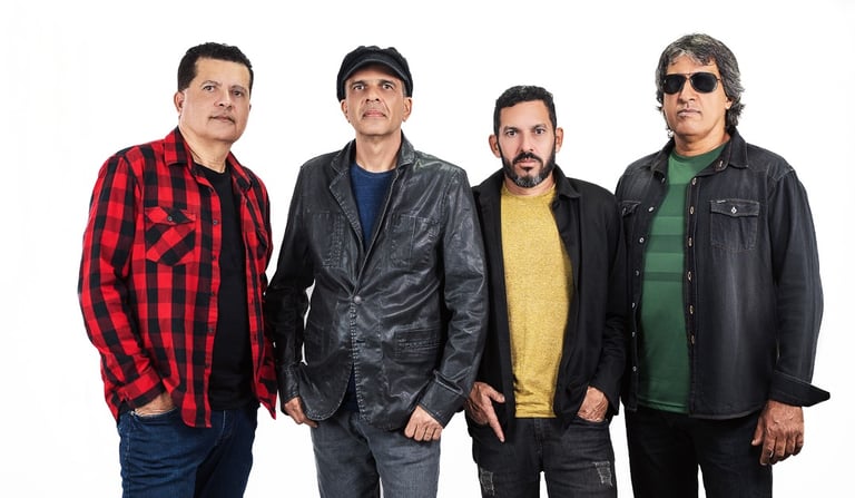 Four male band members in casual rock attire posing against a white background.
