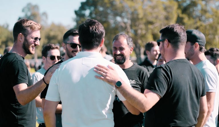 A group of diverse men talking and smiling at a casual outdoor networking event.