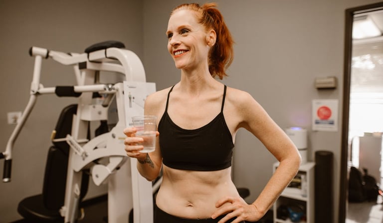WOMAN IN A GYM TAKING SUPPLEMENT IN A GLASS