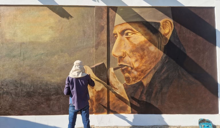 An artist creates a large street art mural of an indigenous shaman smoking a pipe