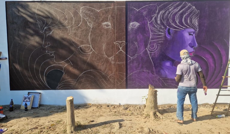 Artist painting a large outdoor mural featuring faces and panthers at centro Mukanranko