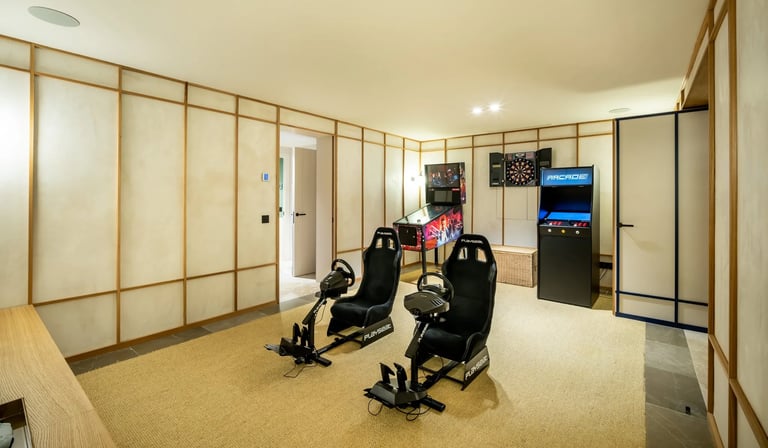 Game room at Villa La Gratitud with racing simulators, arcade machines, and darts