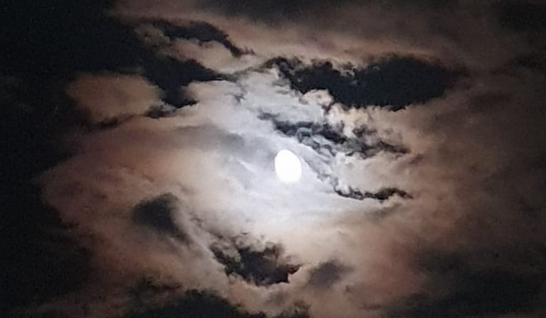 a full moon in the sky with clouds shot during night boat tour