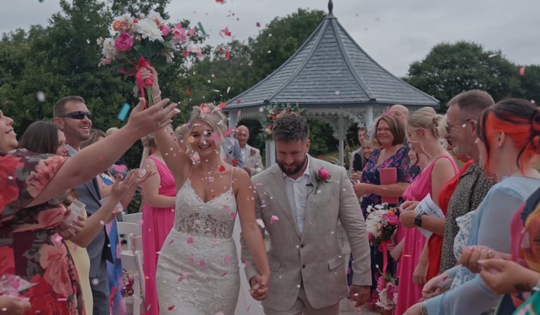 bride and groom walking while guest throw confetti
