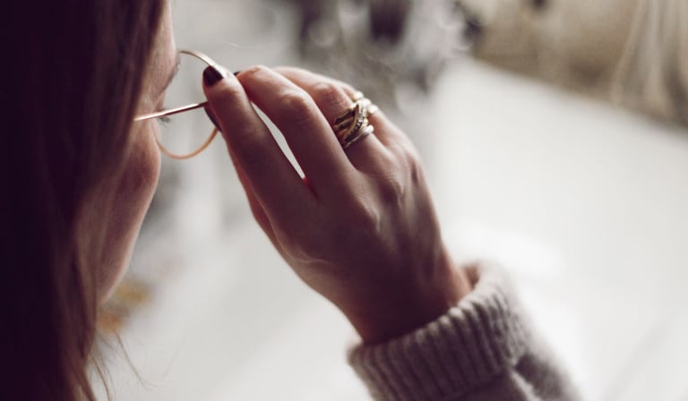 a woman in a sweater and glasses is holding a pair of glasses